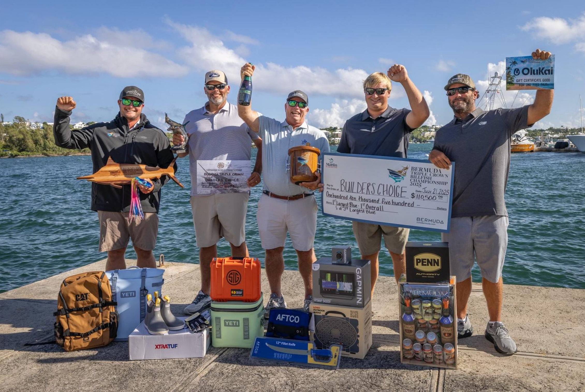 The Builder’s Choice team celebrating their Bermuda Triple Crown Championship win, holding trophies, a large check, and sponsor prizes on the dock in Bermuda.