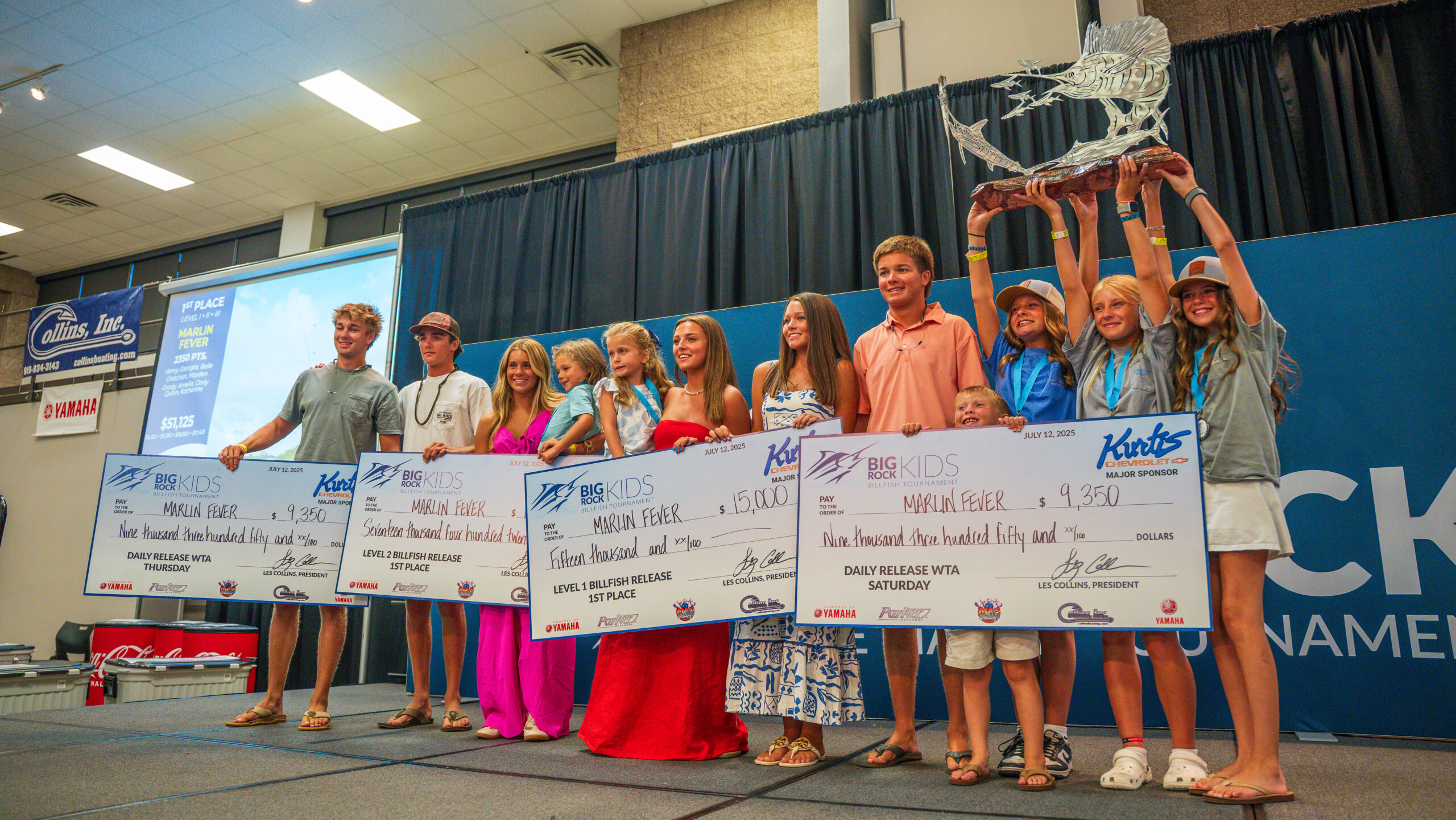 Marlin Fever team on stage with four prize checks and trophy at Big Rock Kids Tournament.